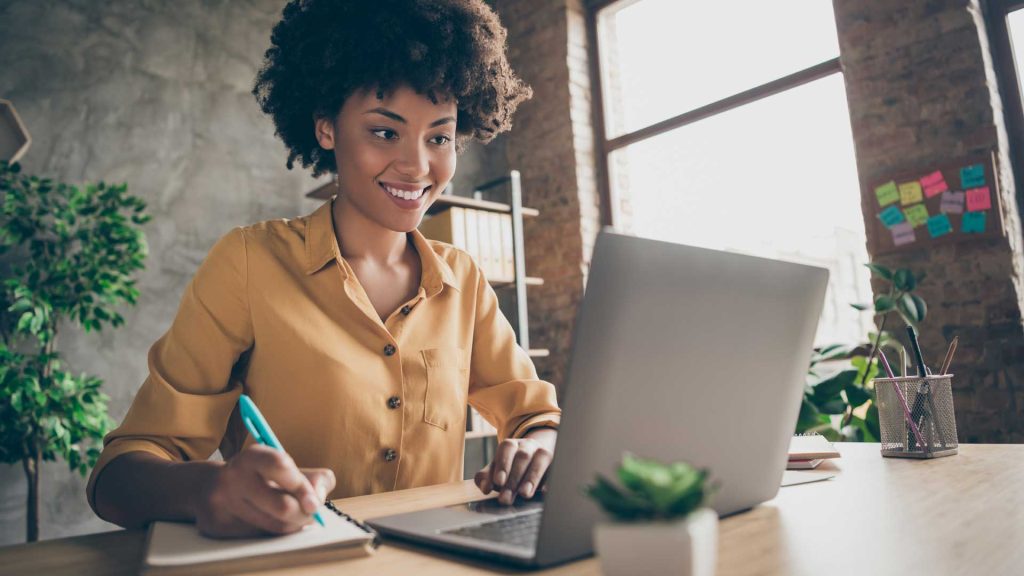 A woman at her laptop taking notes